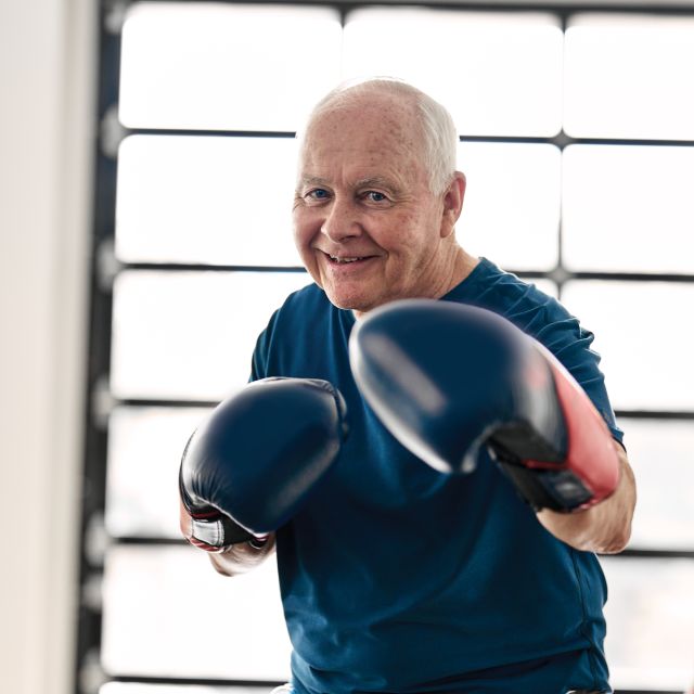 An older adult wearing boxing gloves