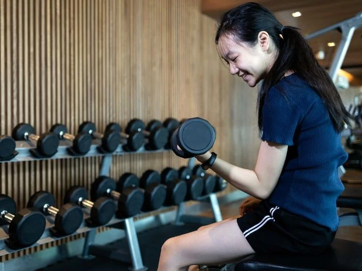 A young person exercising with a dumbbell